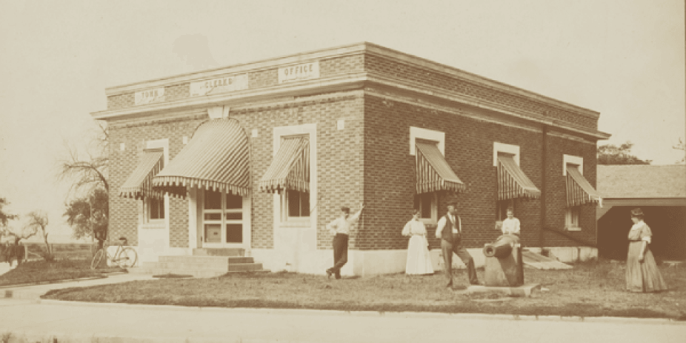 vintage photo of a group of people standing outside a brick Town Clerk's Office